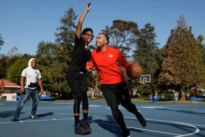 A man and two teens playing basketball at a park—capturing energy and teamwork.