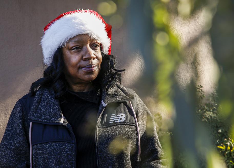 A woman in a Santa hat smiles on a sunny day—expressing cheer and community.