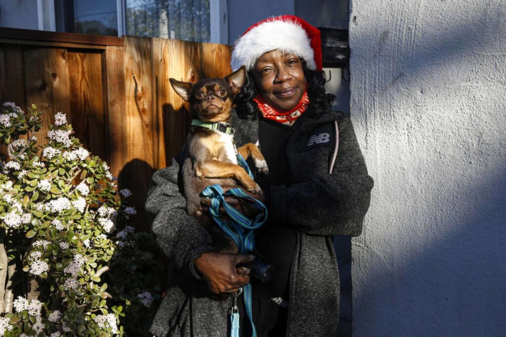 A woman in a winter hat holds a small dog—portraying warmth and companionship.