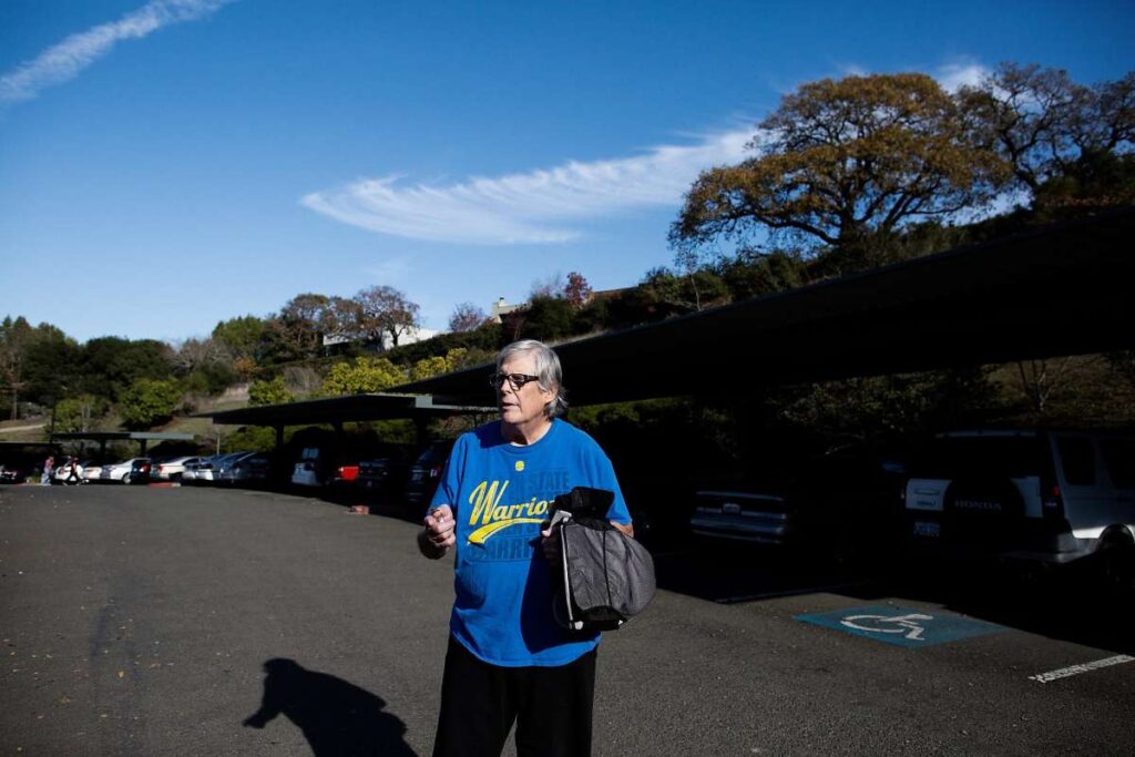 Older man walking through a parking lot.