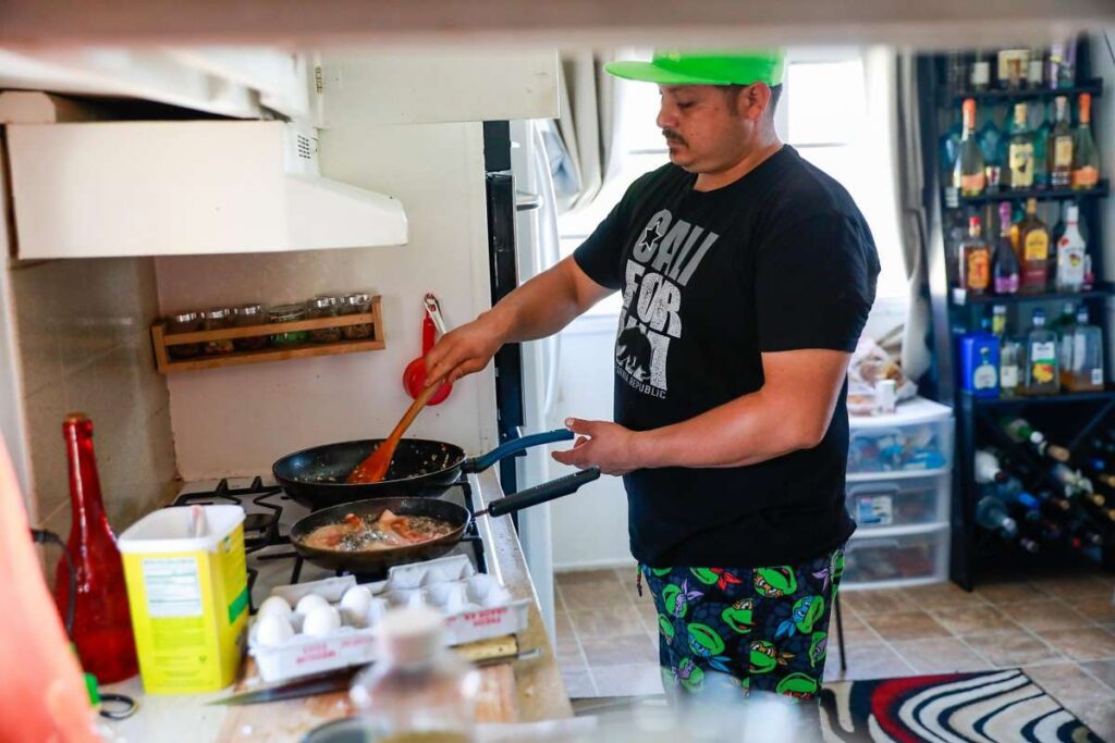 Man cooks at a stove in kitchen.