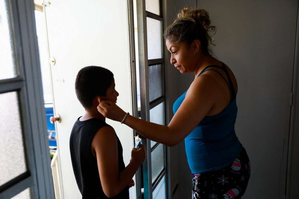 Woman embraces her child in a doorway.