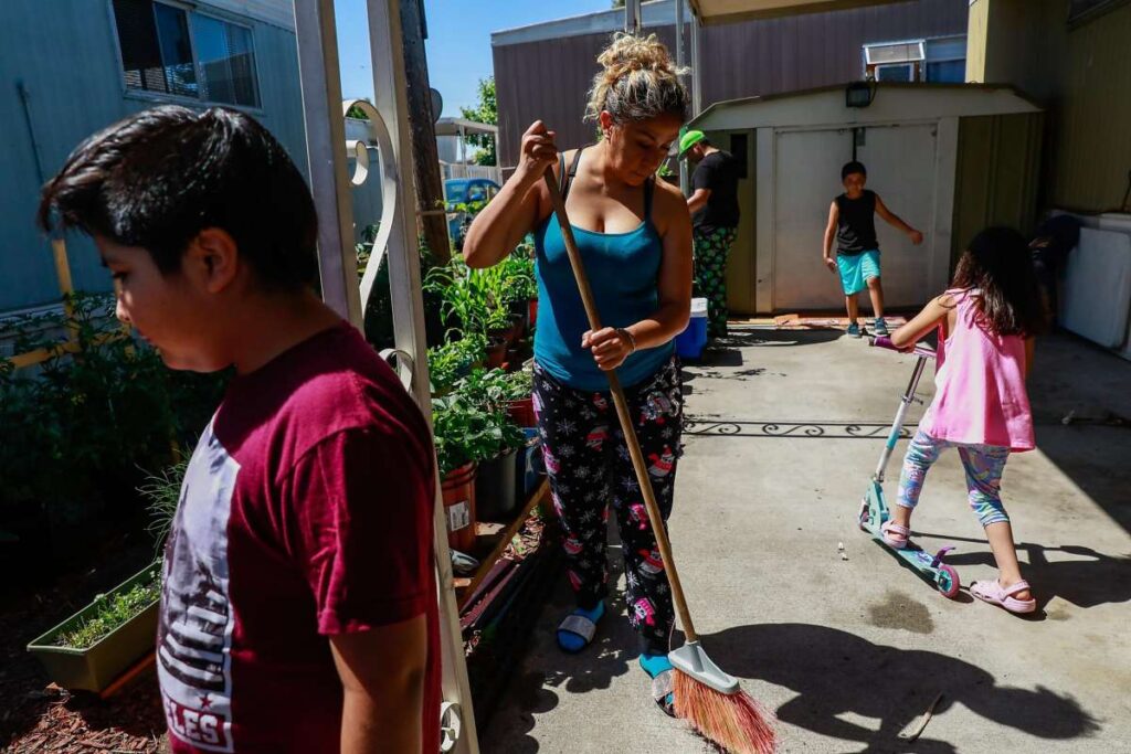 Woman in a front yard garden with children.