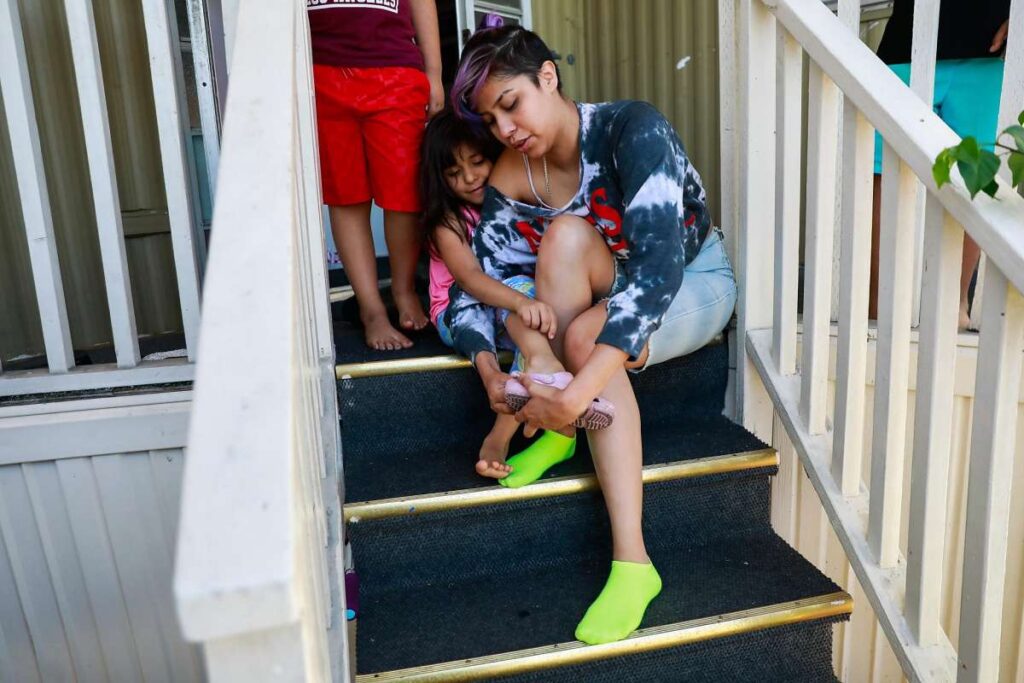 Child sits on outdoor steps with mother.