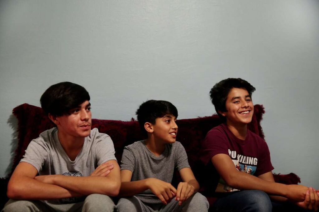 Group of boys sitting on a couch watching something together.