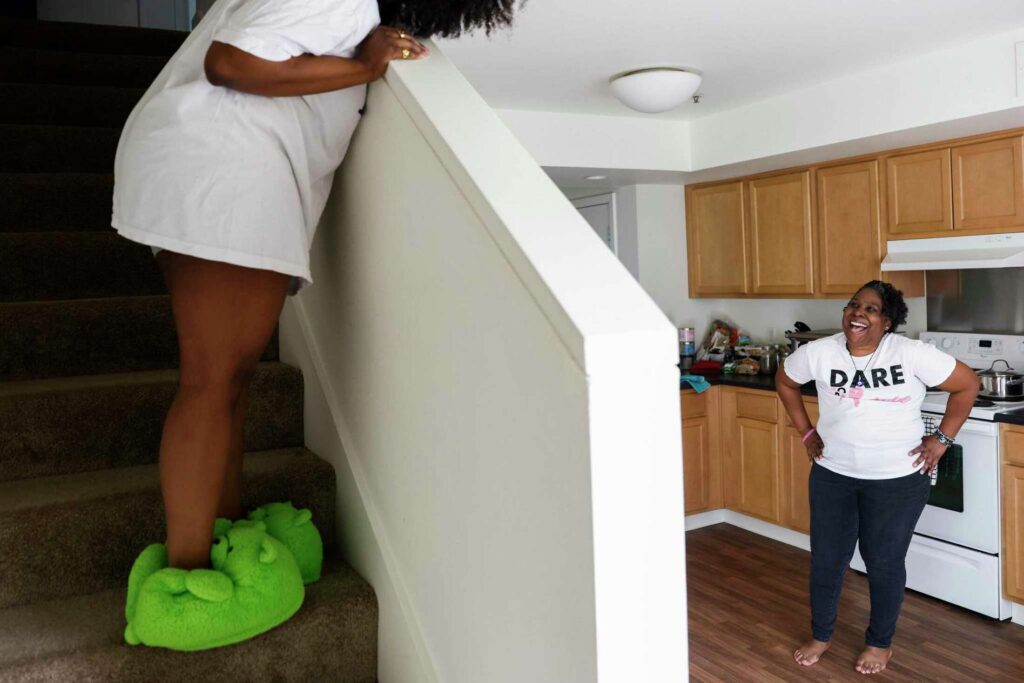 A woman stands on stairway while greeting her friend—capturing home and family.