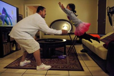 A young girl in a pink tutu dances joyfully with father—capturing laughter, bonding, and play.
