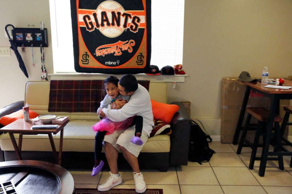 A father and child sit on a couch under a “Giants” banner—showing comfort, childhood, and team spirit.