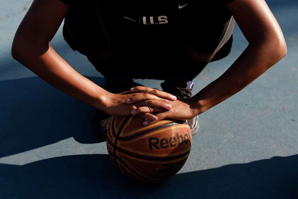 Close-up of a person’s hands resting on a basketball—symbolizing focus and determination.