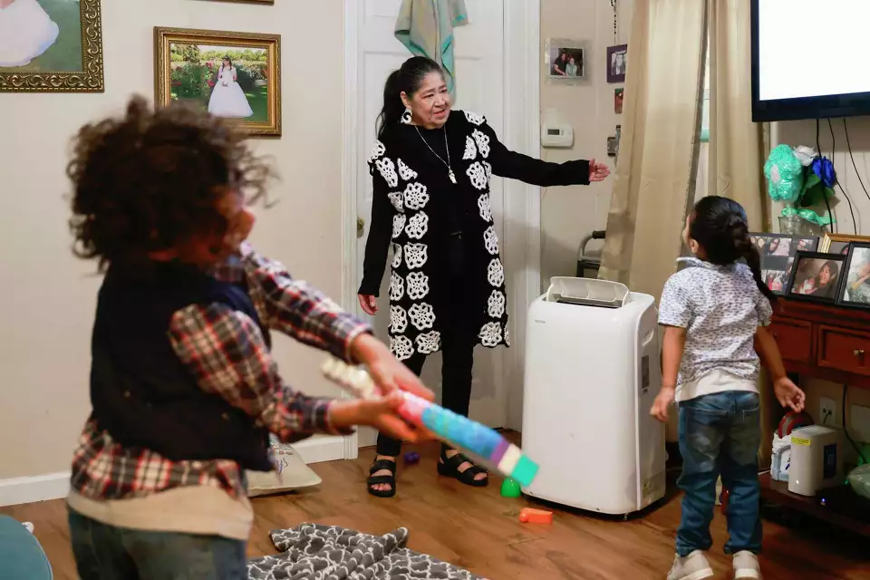 A woman and a young girl holding toys in a modest room—capturing playfulness in a home environment.