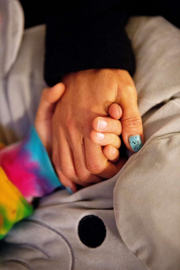 Close-up of two people holding hands.