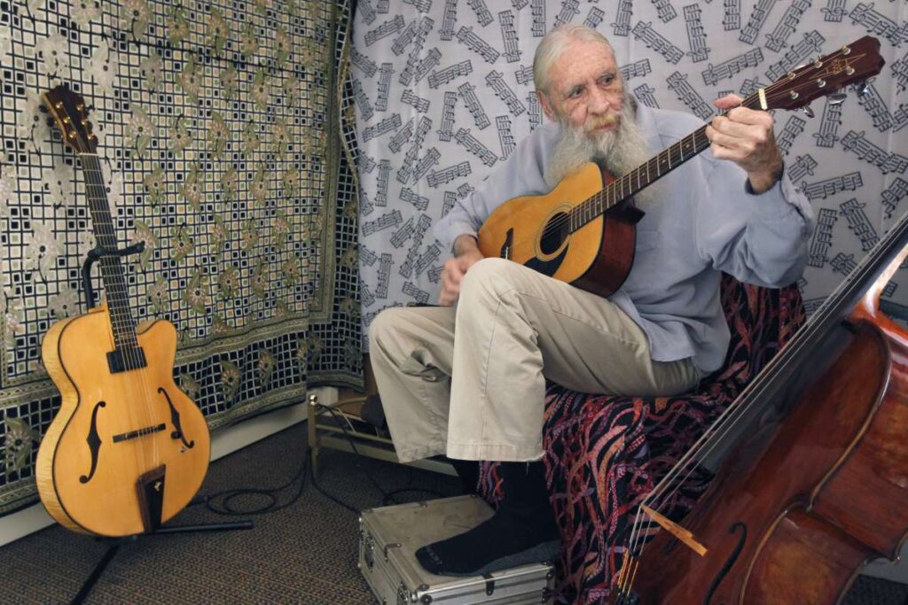 Elderly man plays guitar.