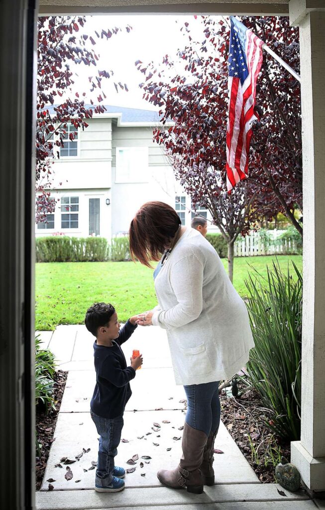Woman holding a child's hand outdoors.
