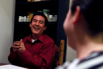 Man smiles while sitting at table.