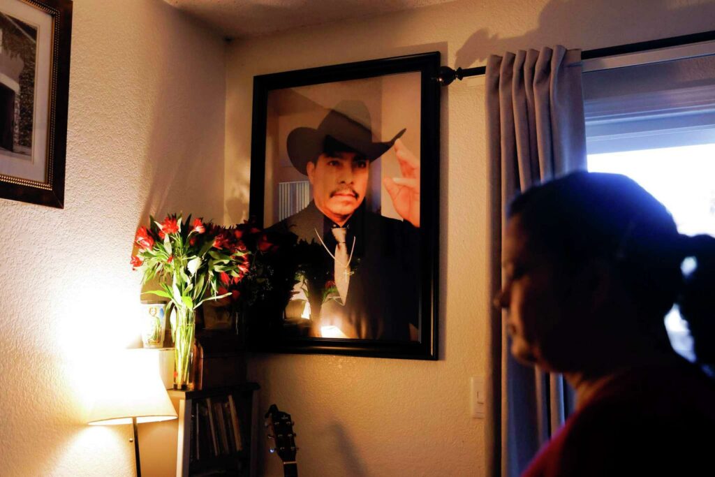 A woman admires a portrait on the wall of a loved one—expressing reflection and love.