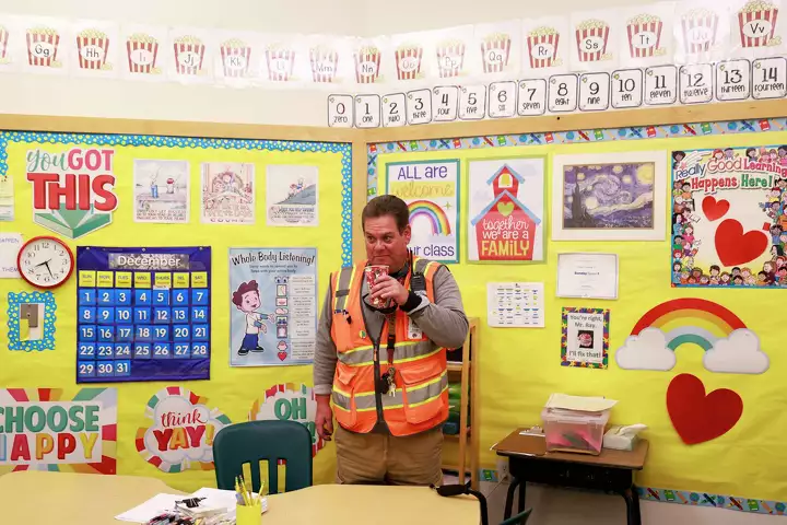 A man smiles in a brightly decorated classroom—celebrating learning and identity.