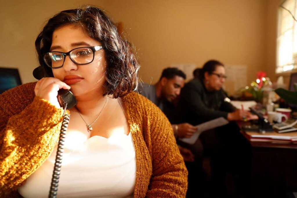 Woman talking on telephone while sitting near others in conversation.