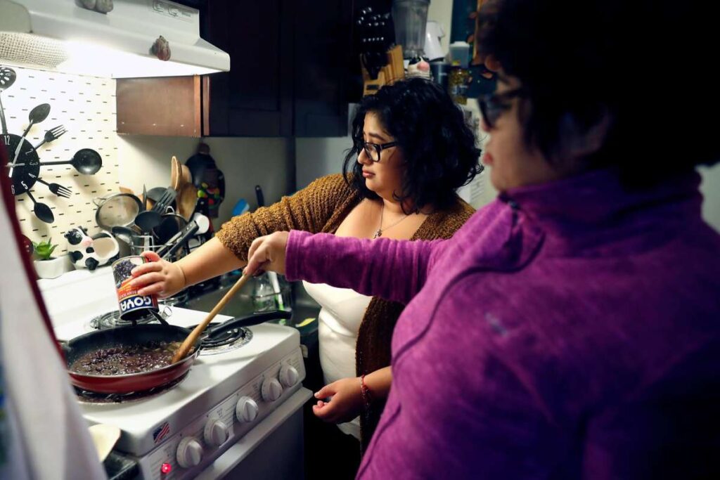 Two women cooking together at a kitchen stove.
