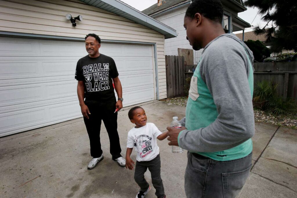 Family of three enjoy each other's company on driveway.