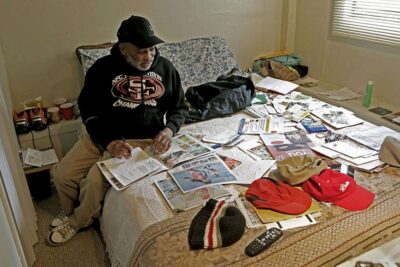Man sorts through mail on bed.