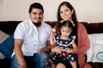 Family of three poses for a portrait in their home.
