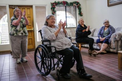 Older woman in a wheelchair smiling with other elders.