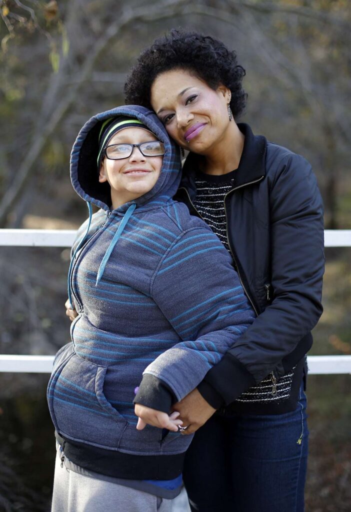 Mother embraces son for photo outdoors.