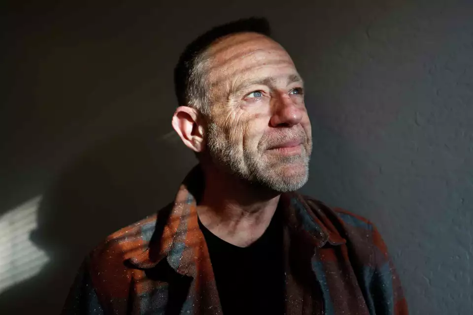 A man gazes into the distance with soft lighting on his face—portraying resilience and introspection.