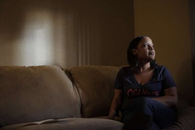 Woman sits on couch staring out the window.