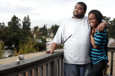Couple poses for photo on apartment balcony.
