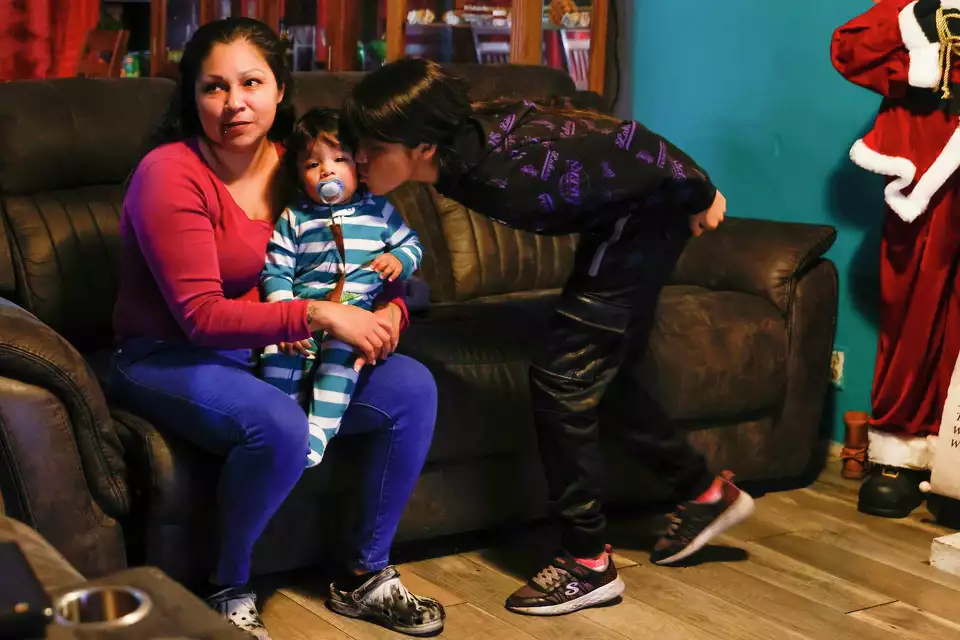 A mother and son sit on a couch as a third person leans in—fostering communication and support at home.