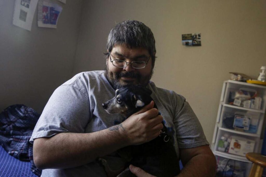 A man holds a a small dog—capturing tenderness and companionship.