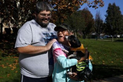 A couple hugs while holding small dog—capturing tenderness and joy.