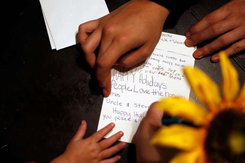 Close up of children's hands writing holiday cards.