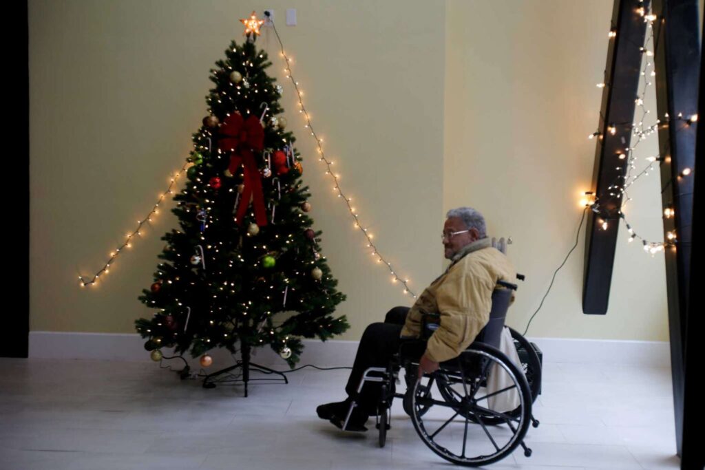 Elderly man in wheelchair admiring Christmas tree.