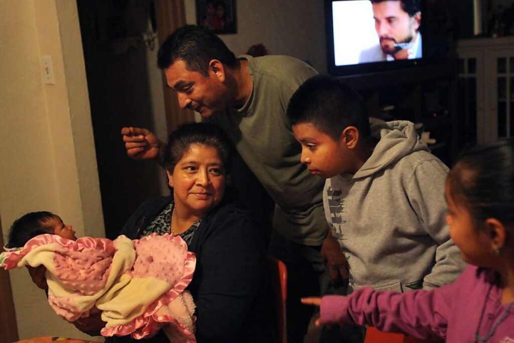 Family huddles around mother holding newborn baby.
