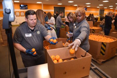 Volunteers packing food into boxes during a group event.
