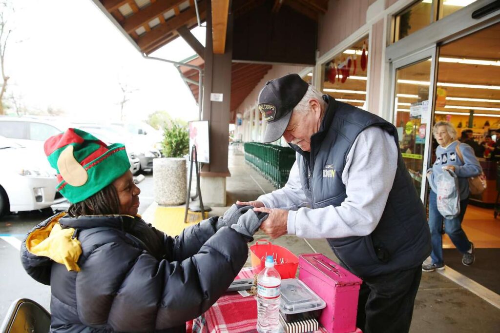Elderly man greets volunteer outside grocery store.