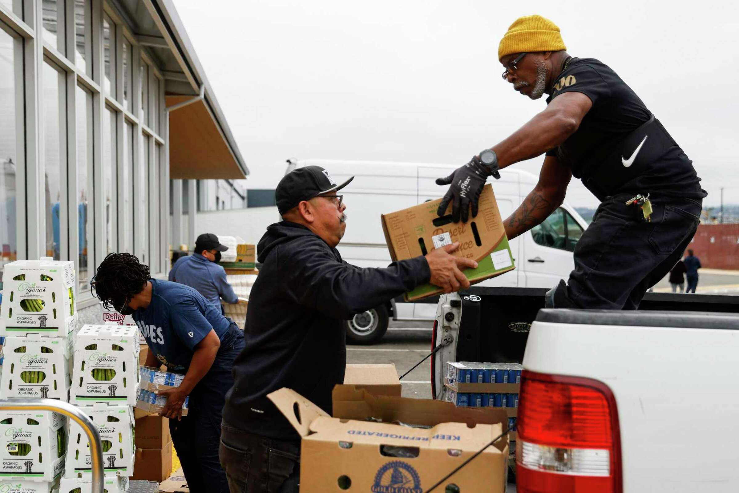 A man lifts a box while another prepares a donation—portraying action and collaboration.