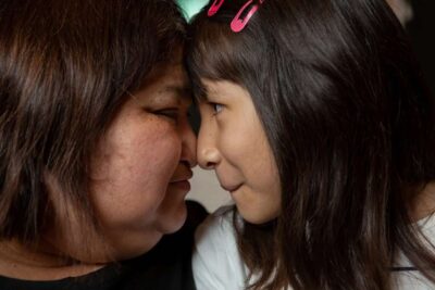 Mother and daughter pressing their foreheads together lovingly.