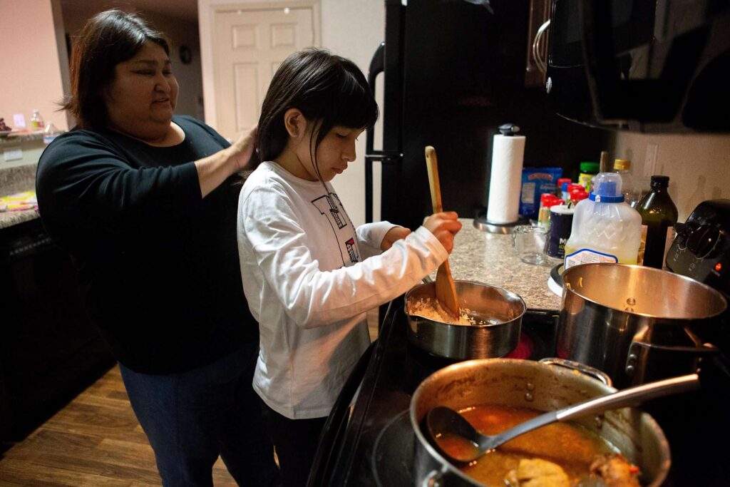 Adult and child stirring ingredients together in a cooking activity.