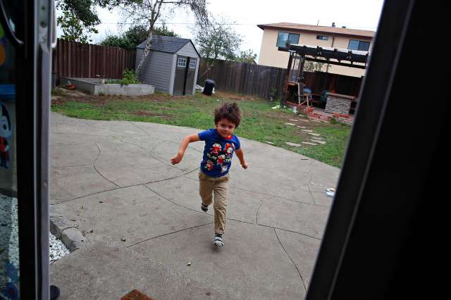 Young boy runs outside from a house with joy.
