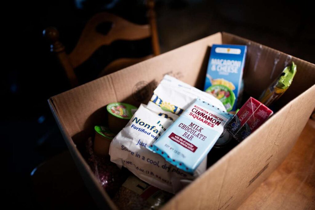 Close-up of snacks and canned goods in a donation box.