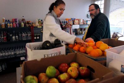 Woman shopping for fresh produce at food pantry with assistance from volunteer.