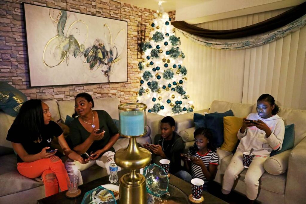 Family sitting in holiday decorated living room together.