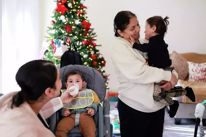 Three generations of women pose in front of a Christmas tree—celebrating community and connection.