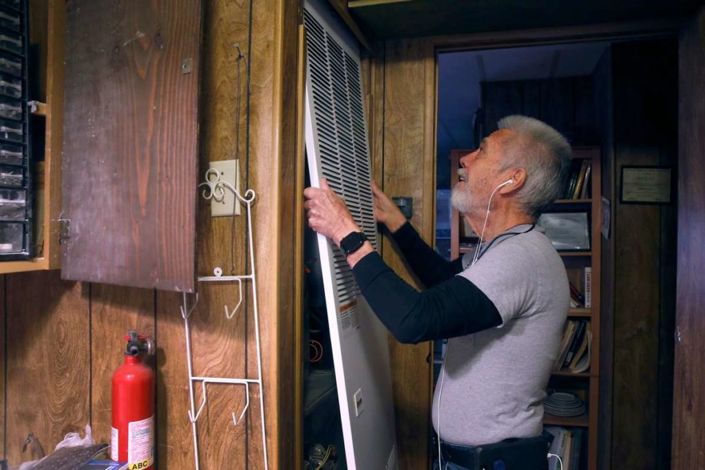 Man reattaches the cover of his heater in house.
