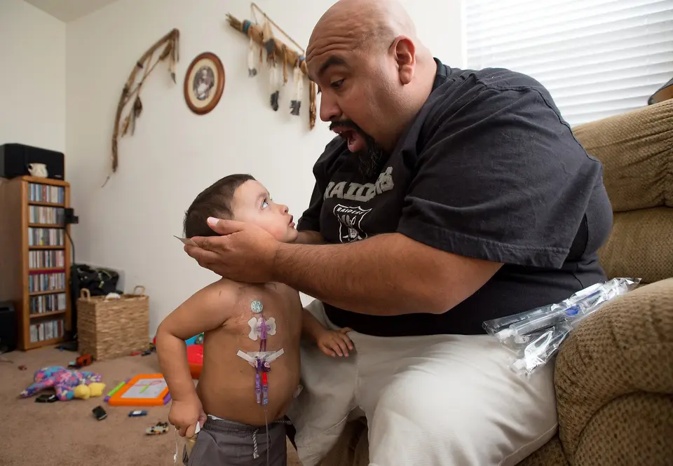 Father holds sickly son affectionately.