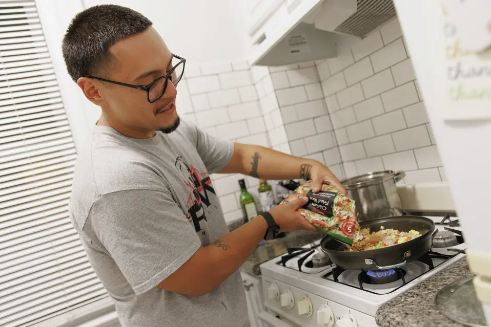 Man cooks food in apartment kitchen.