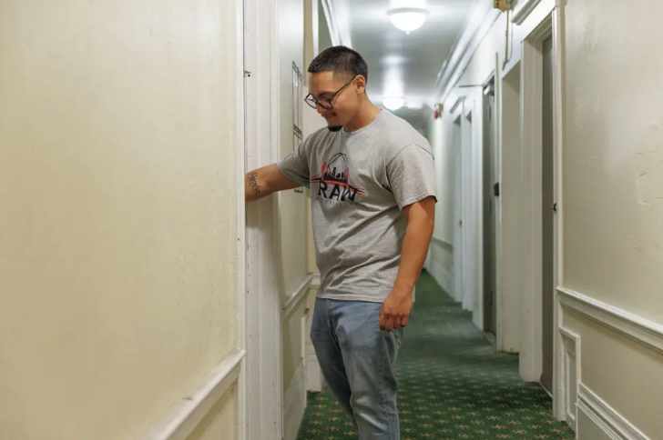 Young man standing in apartment building hallway.